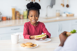 Pertty little black girl showing her tasty sandwich, a Photo by Prostock-Studio