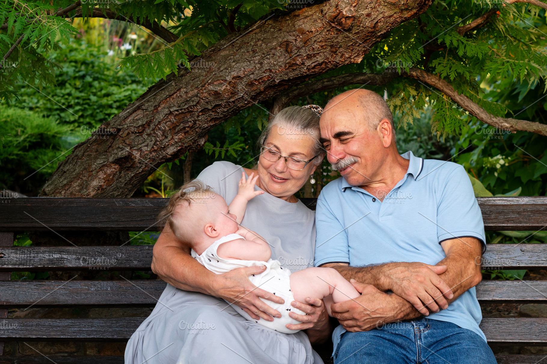 Elderly couple joyfully holding baby, a Person Photo by Elena Vagengeim