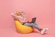 Relaxed freelancer lady leaning back in beanbag chair, resting while working on, a Photo by Prostock-Studio (Thumbnail 2 of 2)