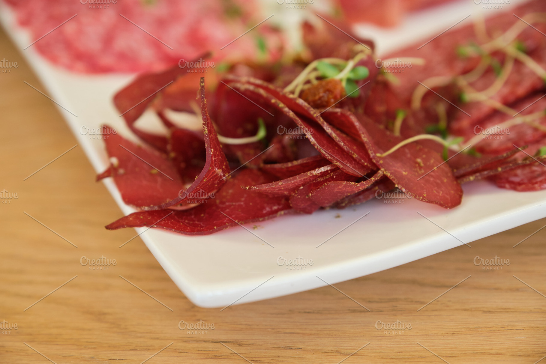 Detailed close-up of thin dried meat slices and spicy salami on white plate., a Food & Drink Photo by Rohan Photography