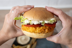 Woman holding crispy chicken burger ready to eat, a Food & Drink Photo by etorres69