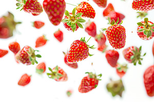 Ripe strawberries flying in the air on white background, a Food & Drink Photo by AlyaAnd