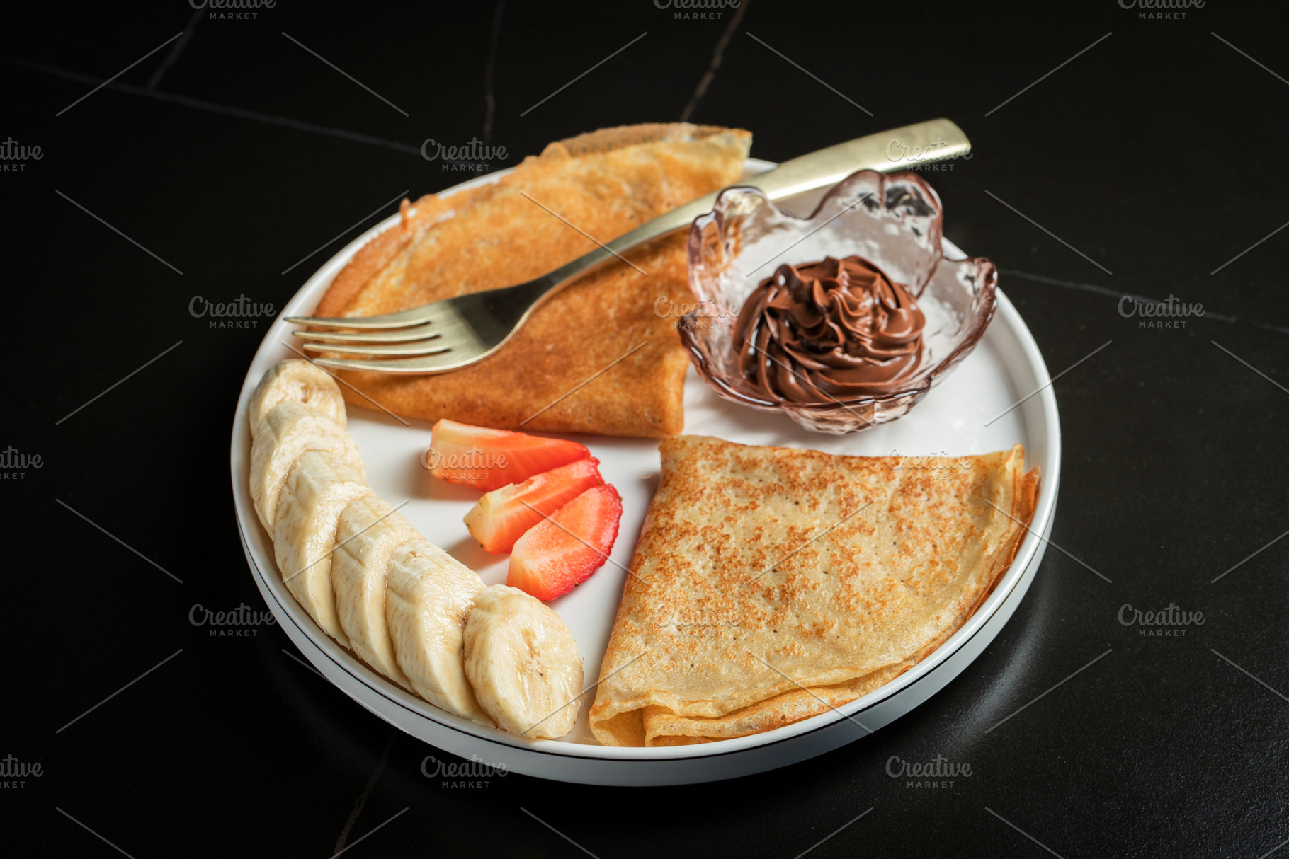 A plate of crepes filled with chocolate spread and topped with b, a Food & Drink Photo by Budarinphoto