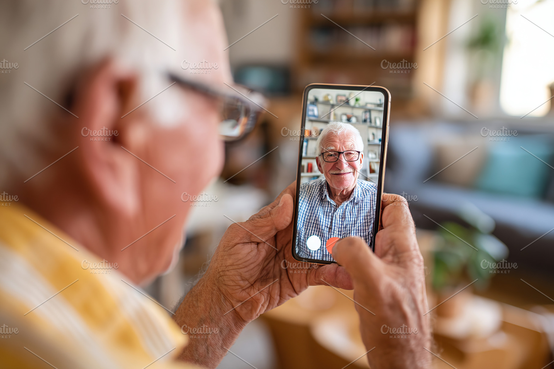 Elderly man using smartphone for video call with family in cozy living room, a Person Photo by AlyaAnd