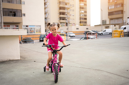 Cute little smiling girl riding bike bicycle in city on parking sunny summer da, a Person Photo by andreonegin market