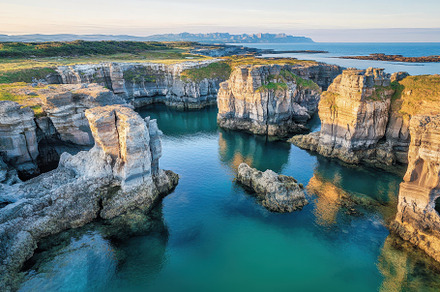 Dramatic rock formations rise from c, a Photo by Tanuart
