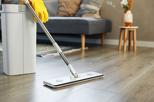 Cleaning supplies: mop, gloves, bucket with wringer on wooden laminate floor, a Business Photo by Lenor4ik