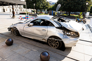 Severely Damaged Silver Sports Car Displayed in a Public Square,