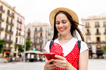 Young adult white tourist woman using mobile phone while walking in the street, a Holiday Photo by Xavier Lorenzo