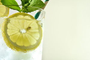 Refreshing drink with lemon, ice and mint with light background, a Food & Drink Photo by Davizro's Market
