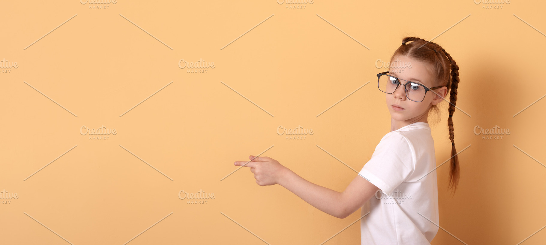 Young girl with glasses and braided hair pointing sideways again, a Person Photo by Ales Munt