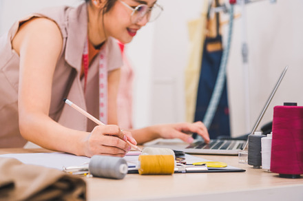 Attractive Asian female fashion designer working in home office, a Person Photo by Ministocker