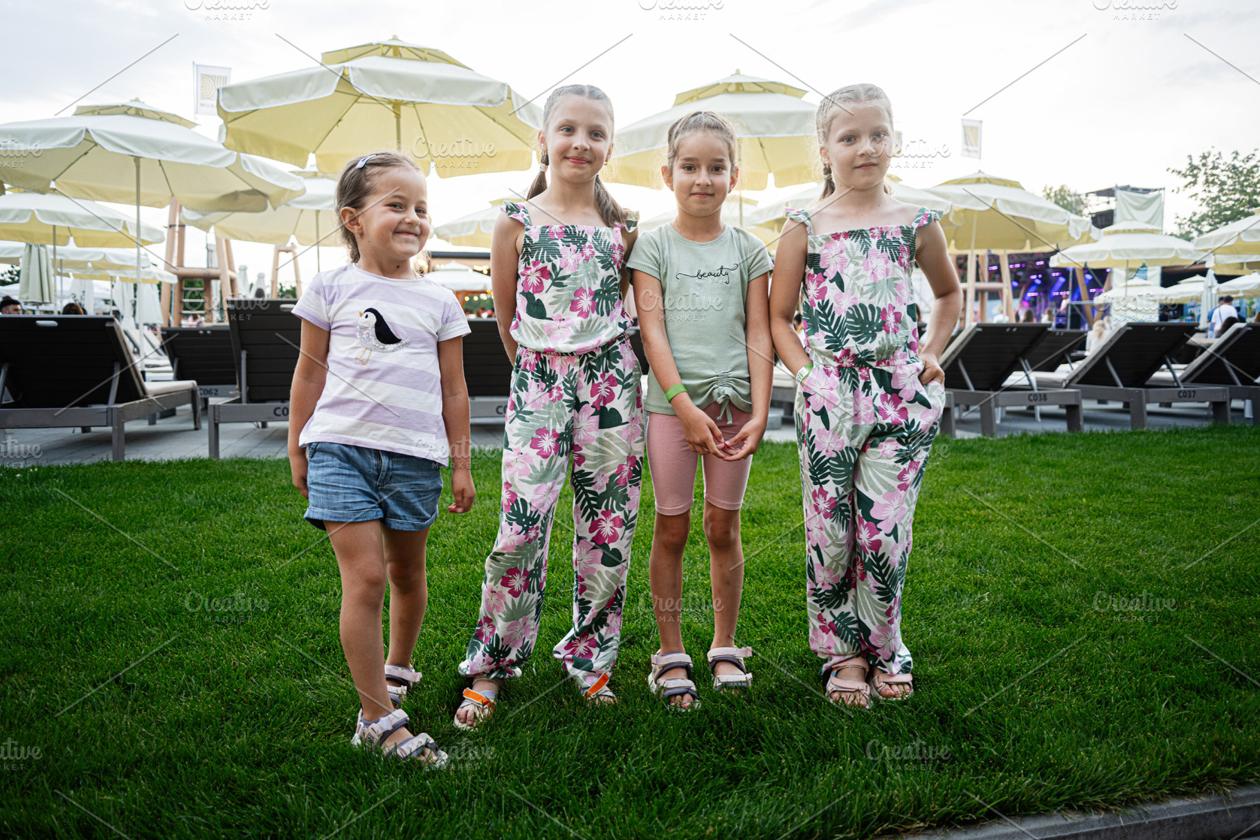 Group of four kids smiling outdoors at a beach resort area, a Photo by AS photostudio