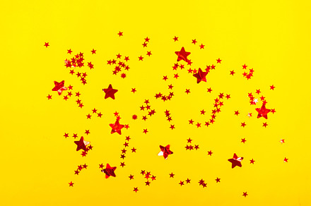 Holidays background with small red glitter stars on yellow backg, a Holiday Photo by vimart