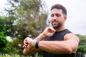 Athletic man checking smartwatch after outdoor workout in park