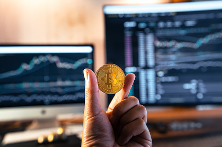 Bitcoin coins in hand in front of the computer, a Business Photo by Art Rachen
