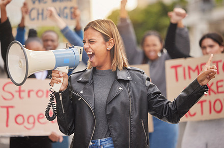 Protest, demonstration and woman with megaphone in city  shouting for justice, freedom and equality. Free speech, human rights and crowd of people marching for social change, revolution and politics, a Photo by Peopleimages.com