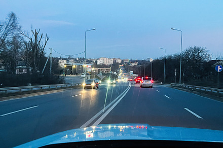 Evening road traffic with cars driving towards the city under a bright sky., a Photo by AS photostudio