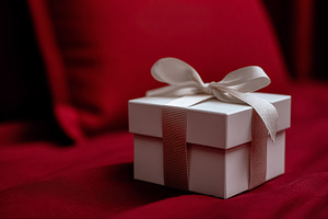 White gift box with ribbon on red background creating a romantic, a Photo by Studio ANNA