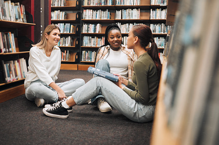 Library, book and group of women reading for education, research and knowledge at university. Discussion, scholarship and female students studying for a test, exam or assignment together at college., a Photo by Peopleimages.com