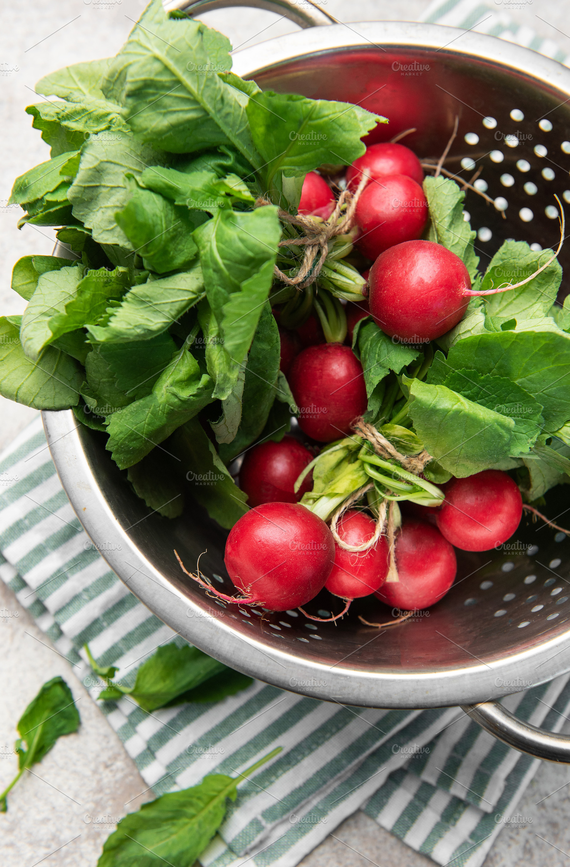 Fresh radishes with green leaves in colander, a Food & Drink Photo by Olena Rudo