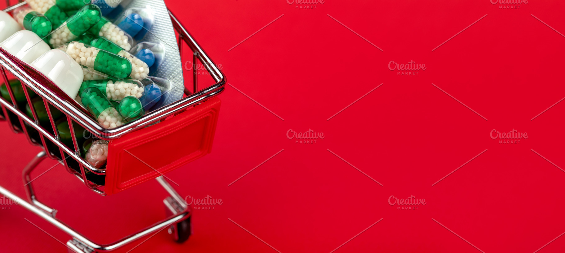 Mini shopping cart filled with various medication capsules and blister packs on, a Health & Medical Photo by Ales Munt