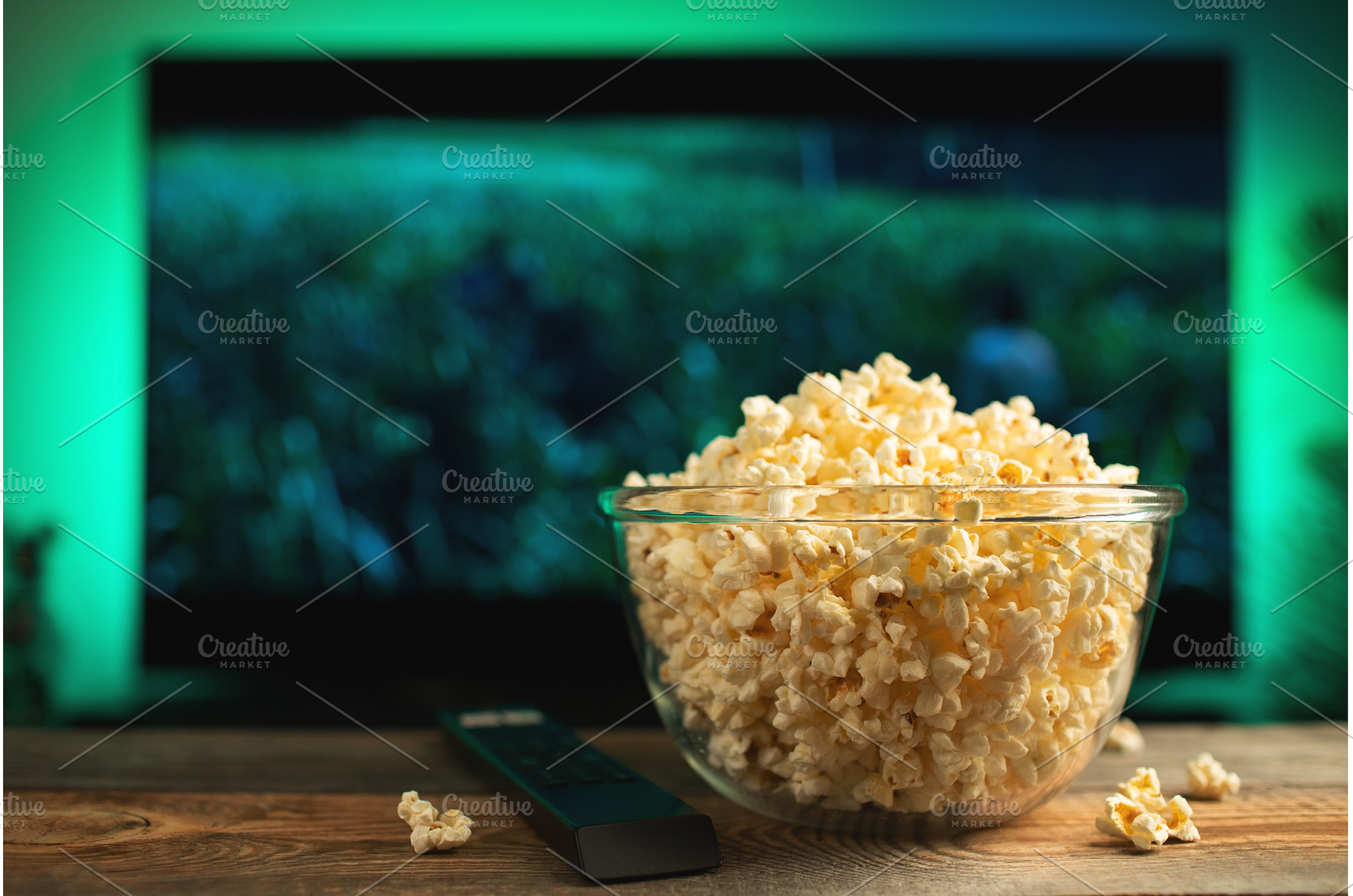 A glass bowl of popcorn and remote, a Technology Photo by Budarinphoto