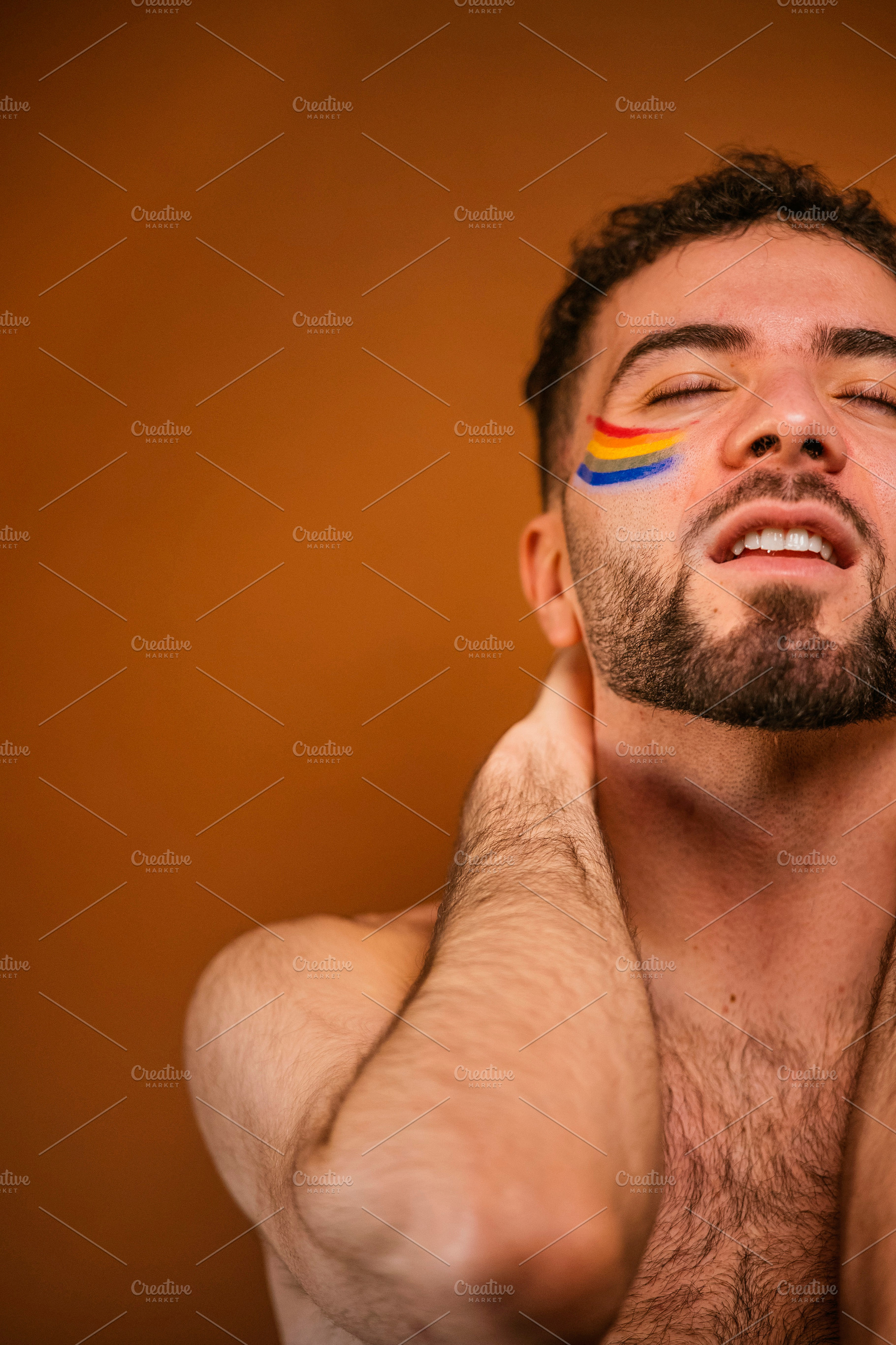 Young man expressing pride with rainbow face paint, a Photo by karrastock