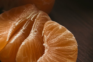 Tangerine fruit segments freshly peeled on a dark wooden table, highlighting he, a Photo by Studio ANNA