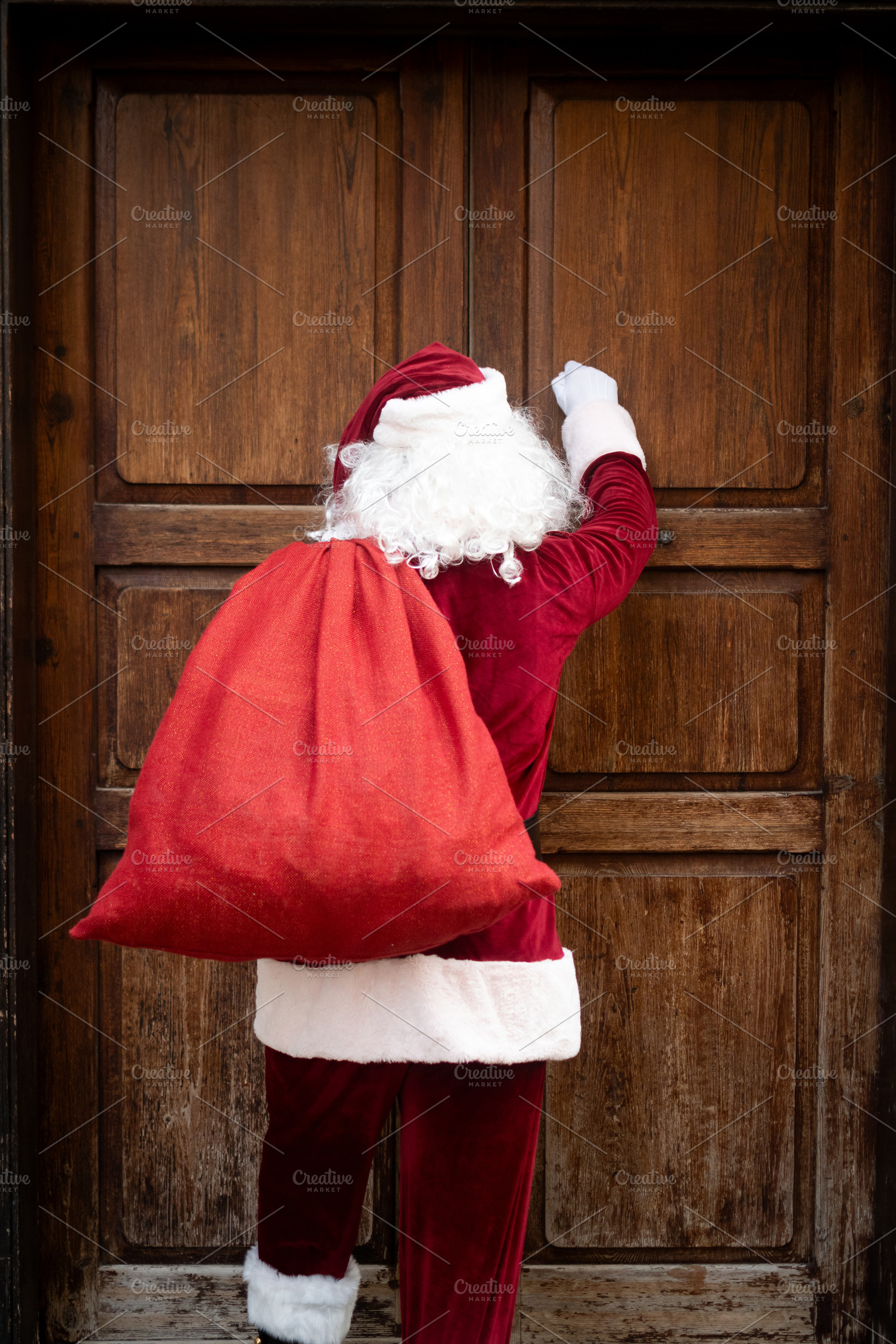 Santa Claus knocking on wooden door with Christmas gift sack, a Person Photo by etorres69