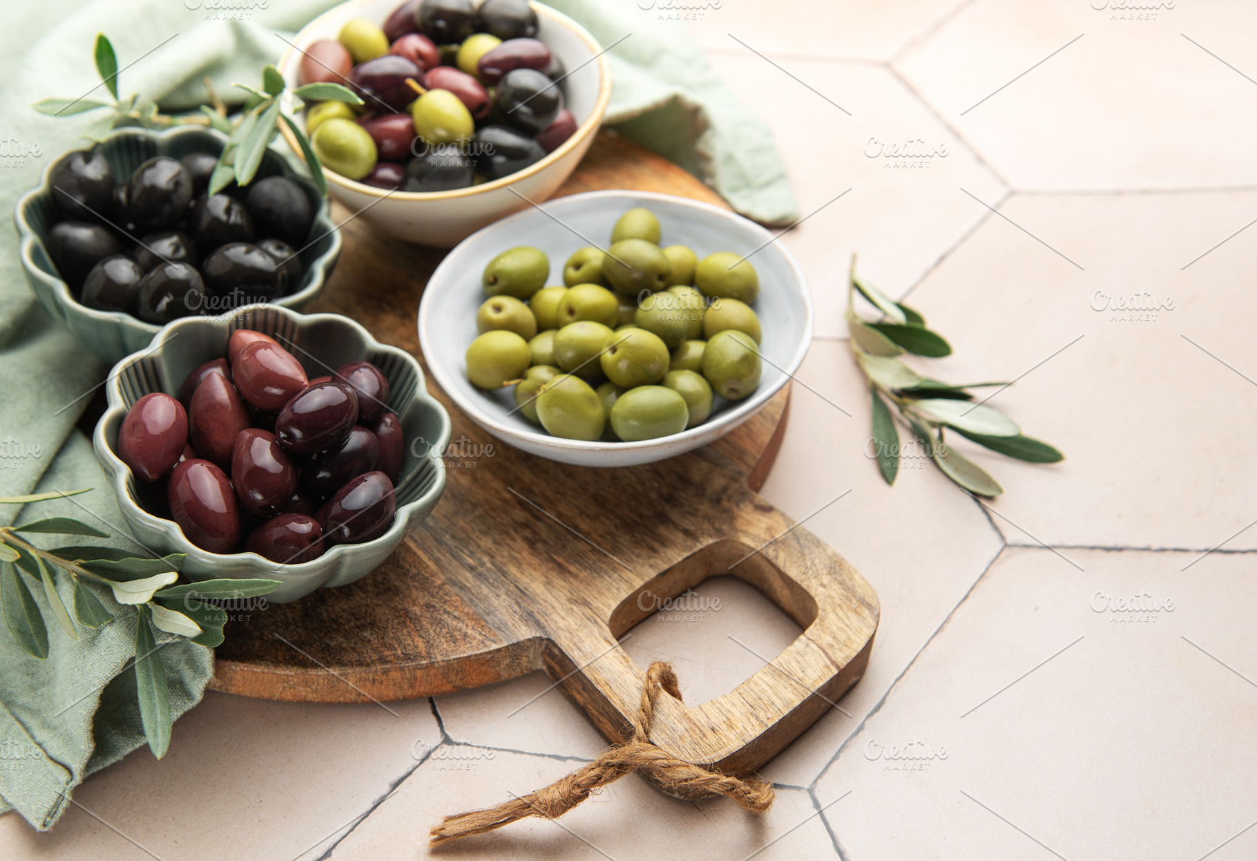 Green, black and kalamata olives in bowls on wooden board, a Food & Drink Photo by Olena Rudo
