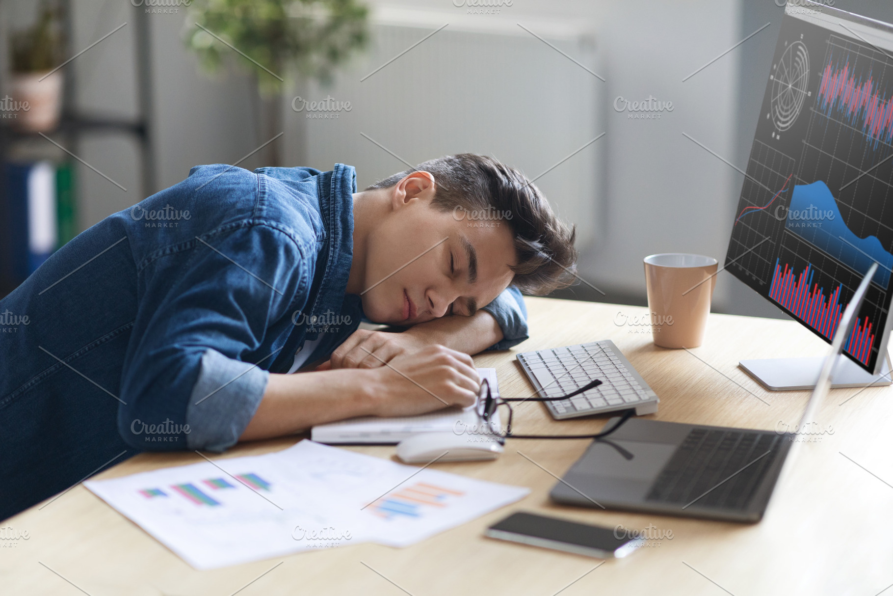 Portrait Of Tired Young Male Employee Sleeping At Work, a Photo by Prostock-Studio
