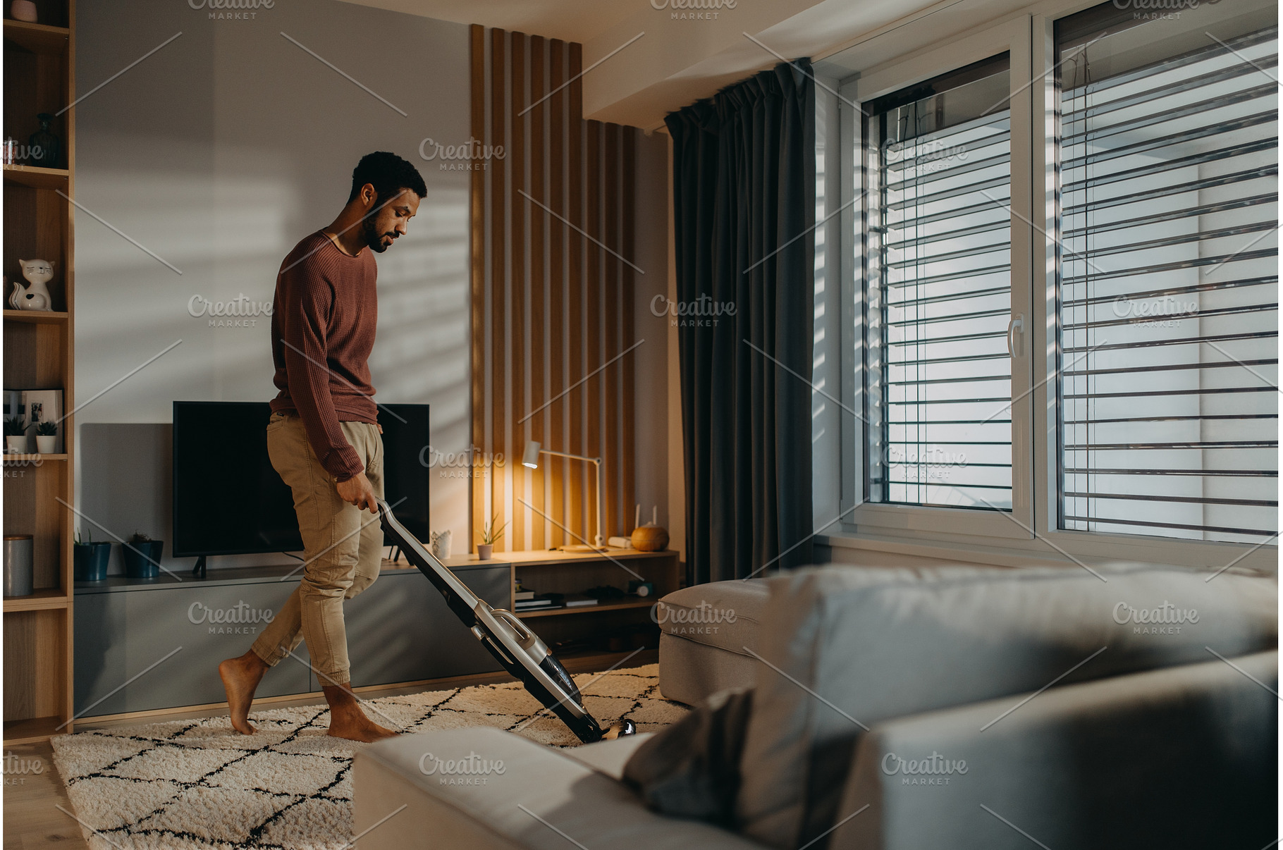 Young man vacuum cleaning carpet in, a Person Photo by HalfPoint