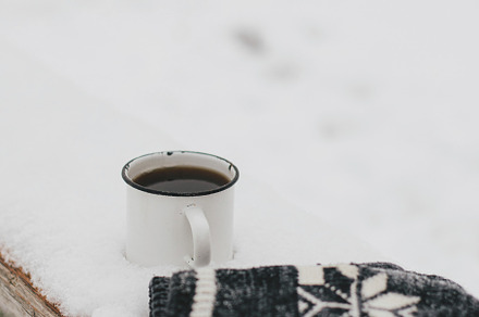 Warm cup of tea and cozy knitted gloves in snow on wooden bench, a Holiday Photo by Sonjachni