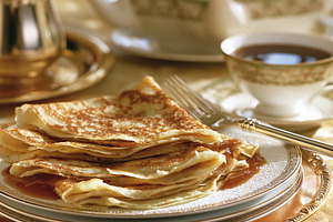 Stack of golden crepes drizzled with syrup, dusted with powdered sugar, served, a Photo by Studio ANNA