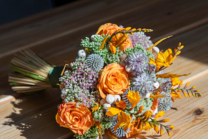Close-up of a floral wedding bouquet featuring bright orange ros