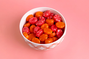 Bright red and orange hard candies in a white bowl on a pink bac, a Food & Drink Photo by Ales Munt
