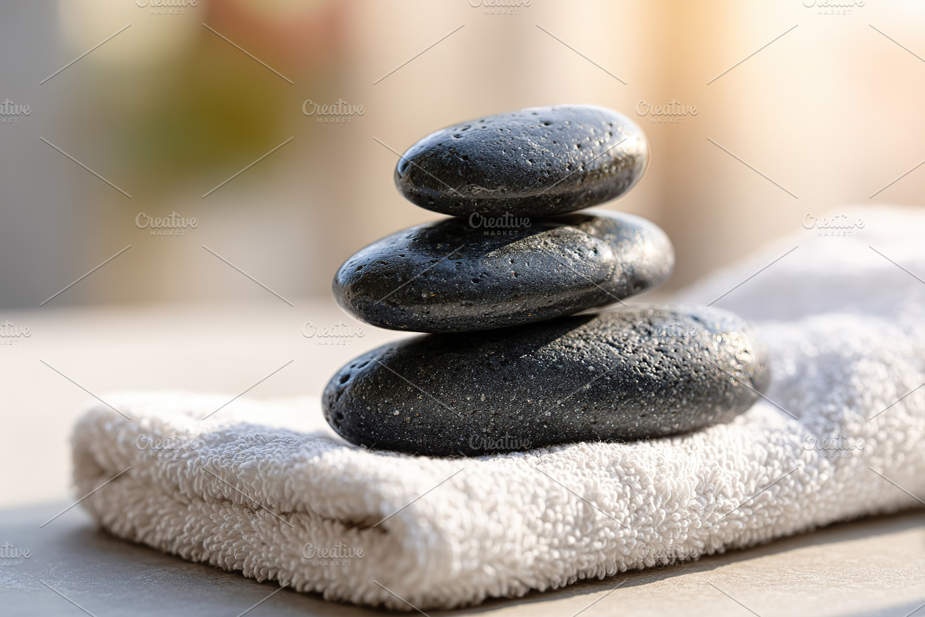 Smooth black basalt spa stones stacked on a soft towel in a tranquil setting, a Photo by AlyaAnd