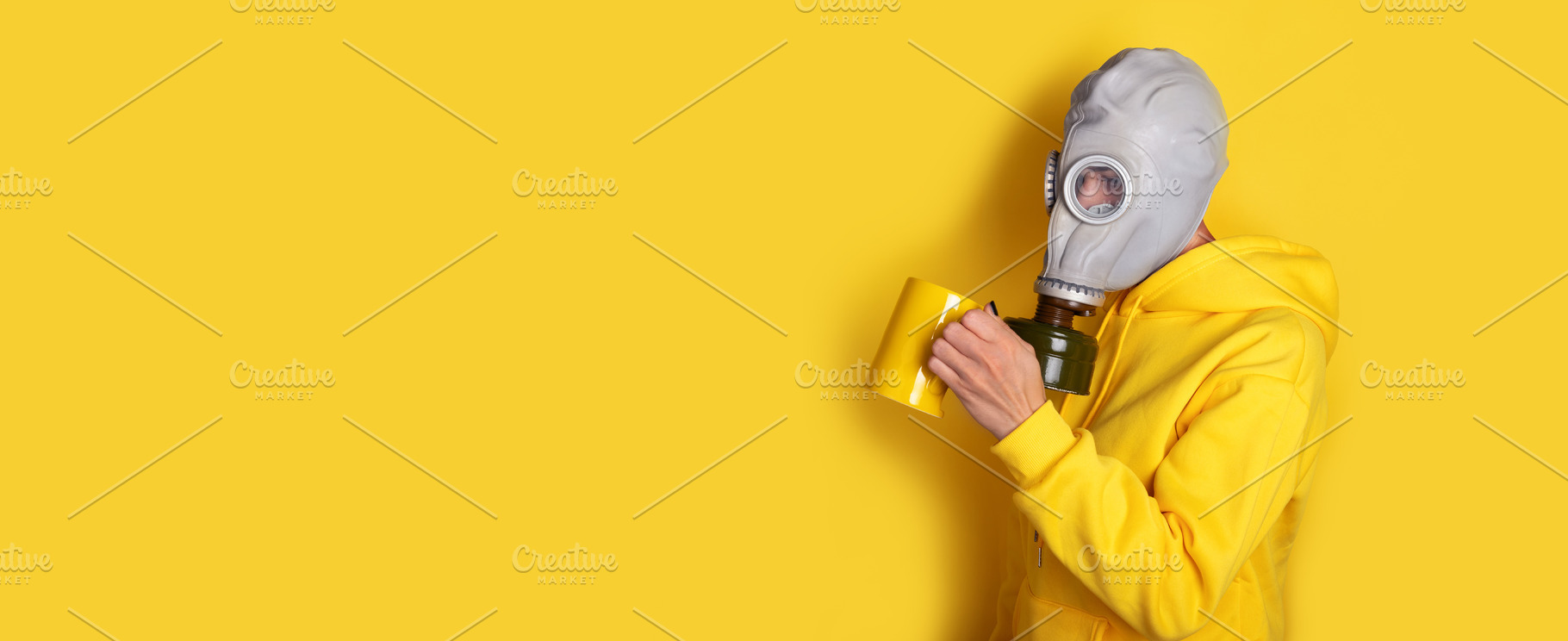 Individual wearing a gas mask and yellow hoodie drinks from a ma, a Person Photo by Ales Munt