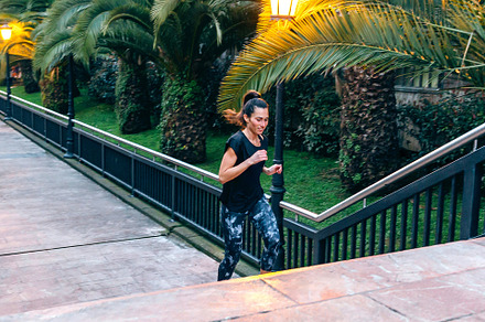 Female runner training up stairs over in urban runway on sunset