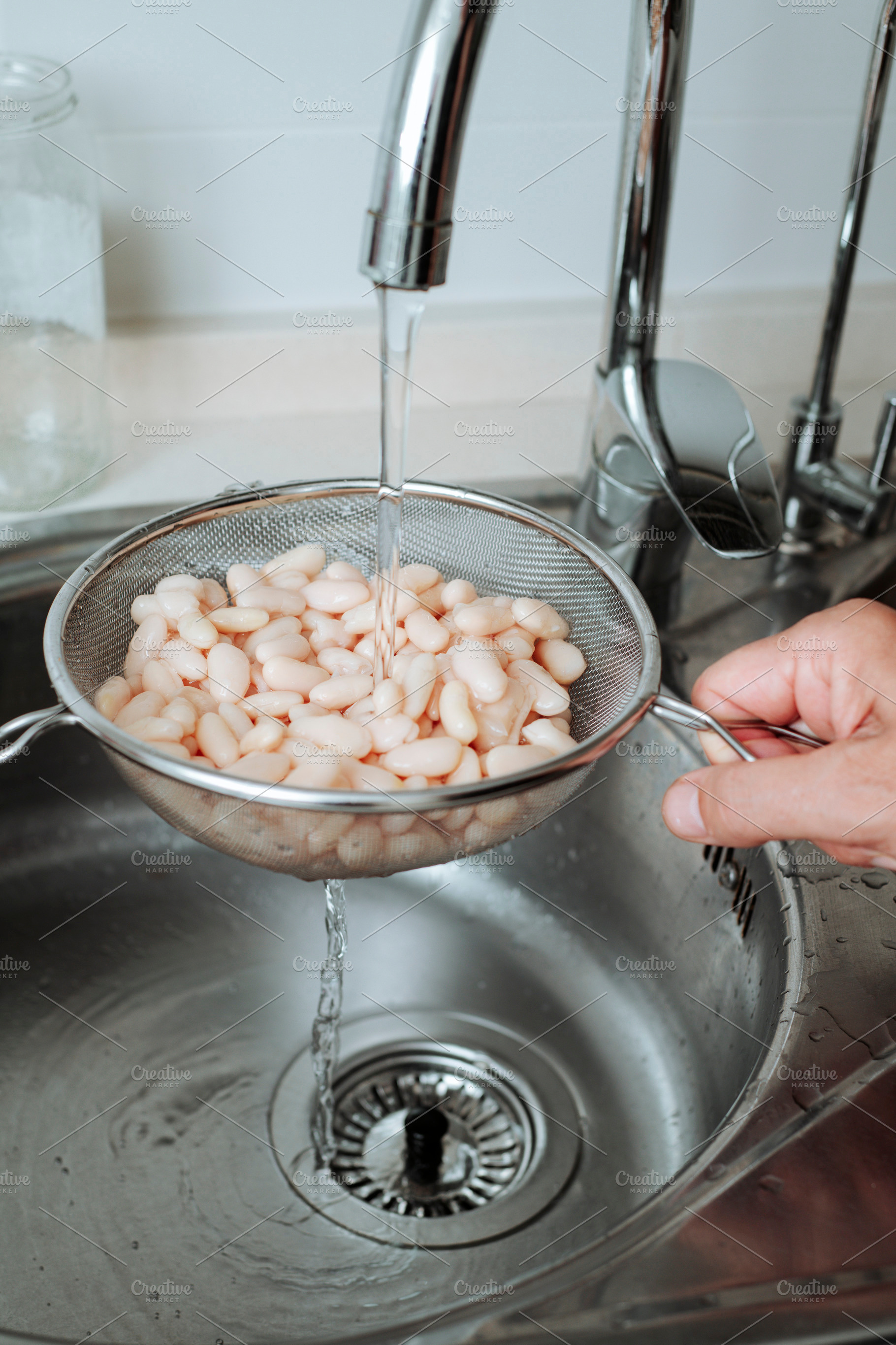 rinsing white beans in the kitchen sink, a Photo by Nito