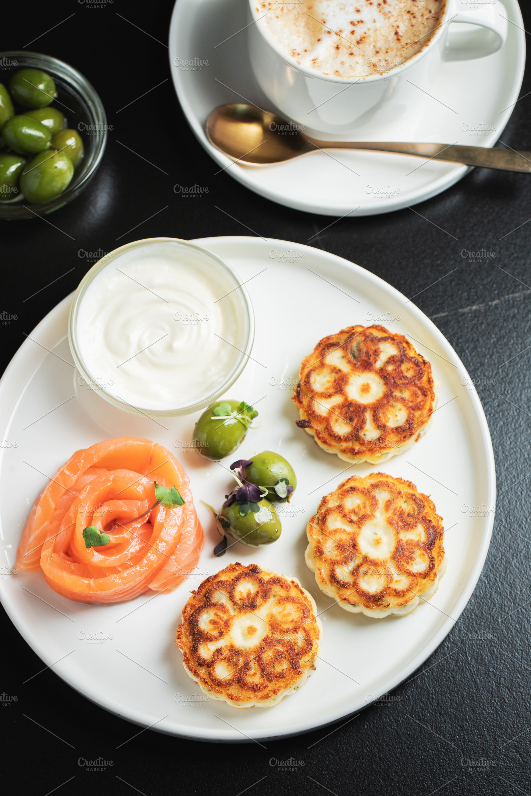 Savory Syrniki with Smoked Salmon, Olives and Sour Cream on White Plate, a Food & Drink Photo by Budarinphoto