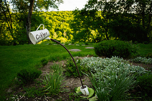 Creative garden decoration with a coffee cup sculpture and lush greenery, a Photo by AS photostudio
