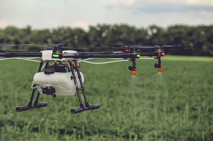 Closeup view of agriculture drone spraying water fertilizer on the green field