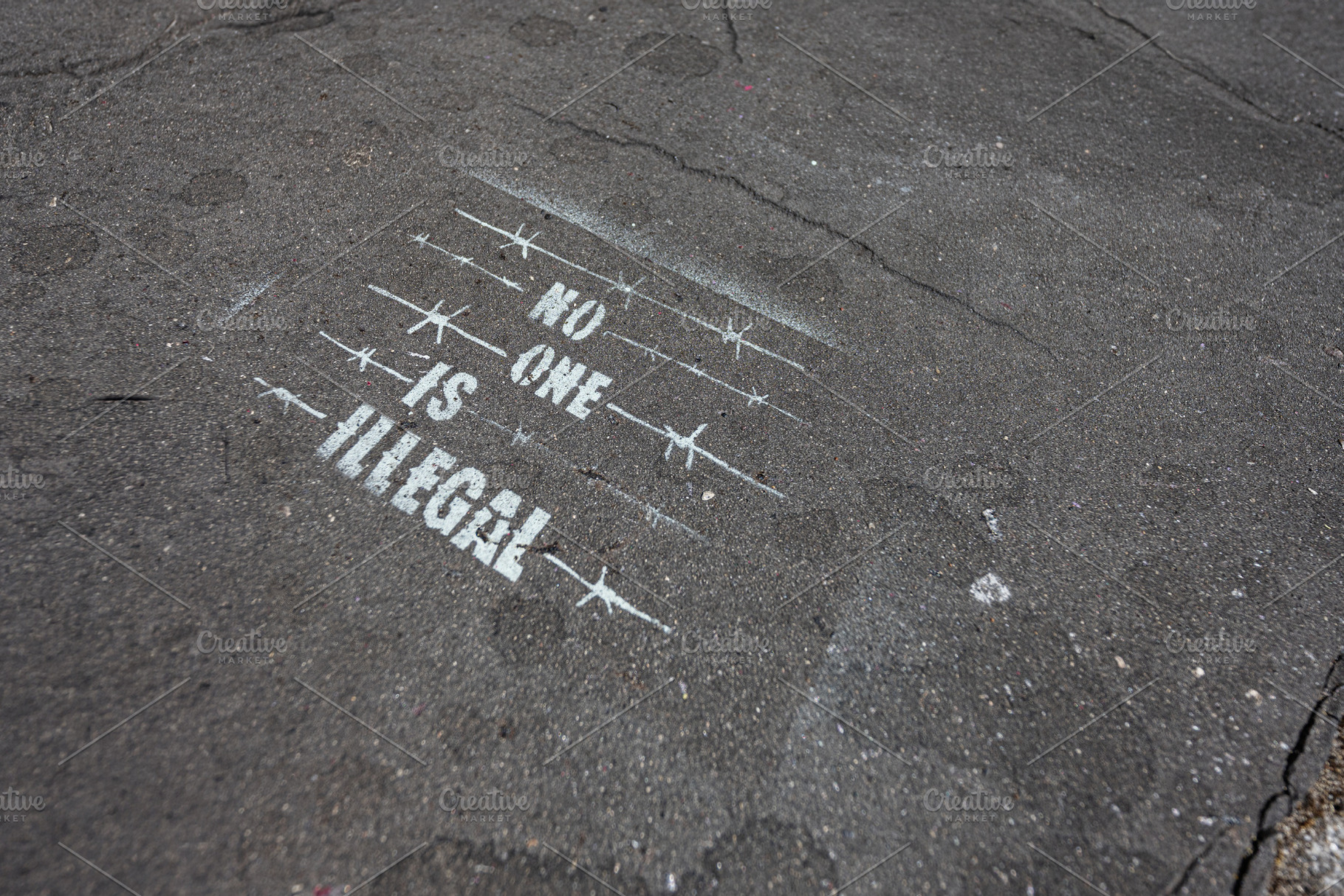 No one is illegal stencil on asphalt street art protesting immigration policy i, a Photo by AS photostudio