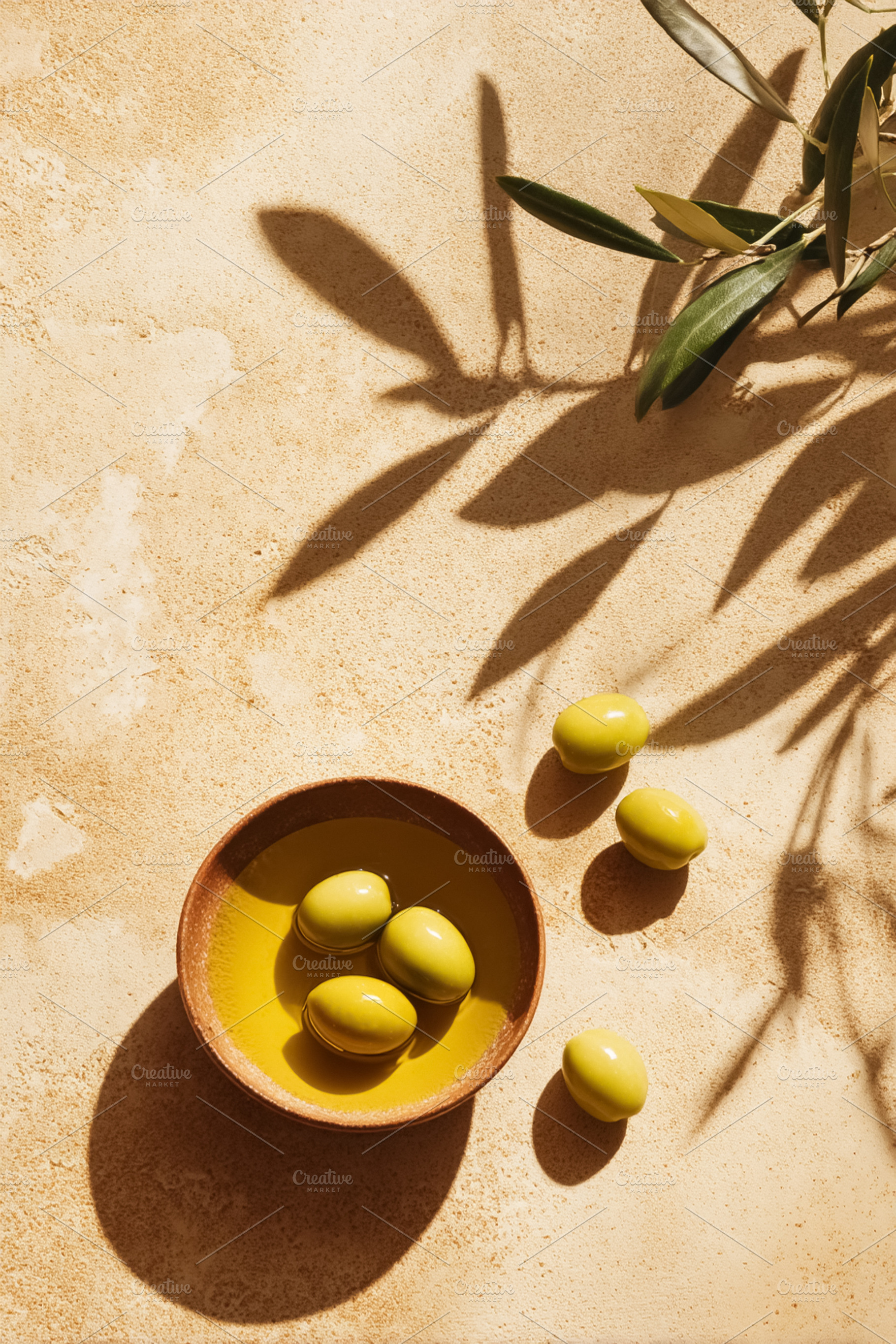 Green olives floating in olive oil bowl on a mediterranean style, a Photo by Studio ANNA