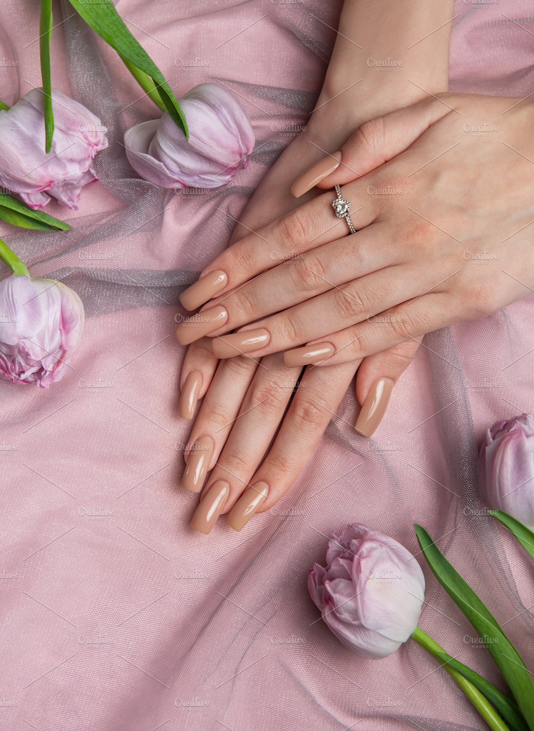 Woman showing nude manicure and diamond ring near tulips on pink, a Beauty & Fashion Photo by Olena Rudo