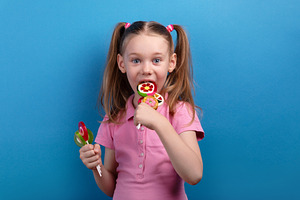 Excited young girl in a pink shirt biting into colorful fruit-sh, a Person Photo by Ales Munt