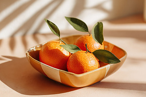 Freshly picked oranges displayed in a colorful bowl on a sunny kitchen countert, a Food & Drink Photo by AlyaAnd