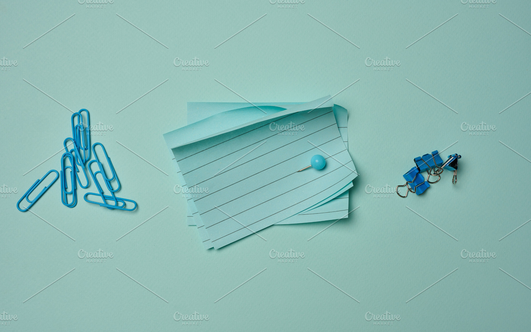 Blue stationery supplies a stack of sheets, paper clips, and pus, a Business Photo by ndanko